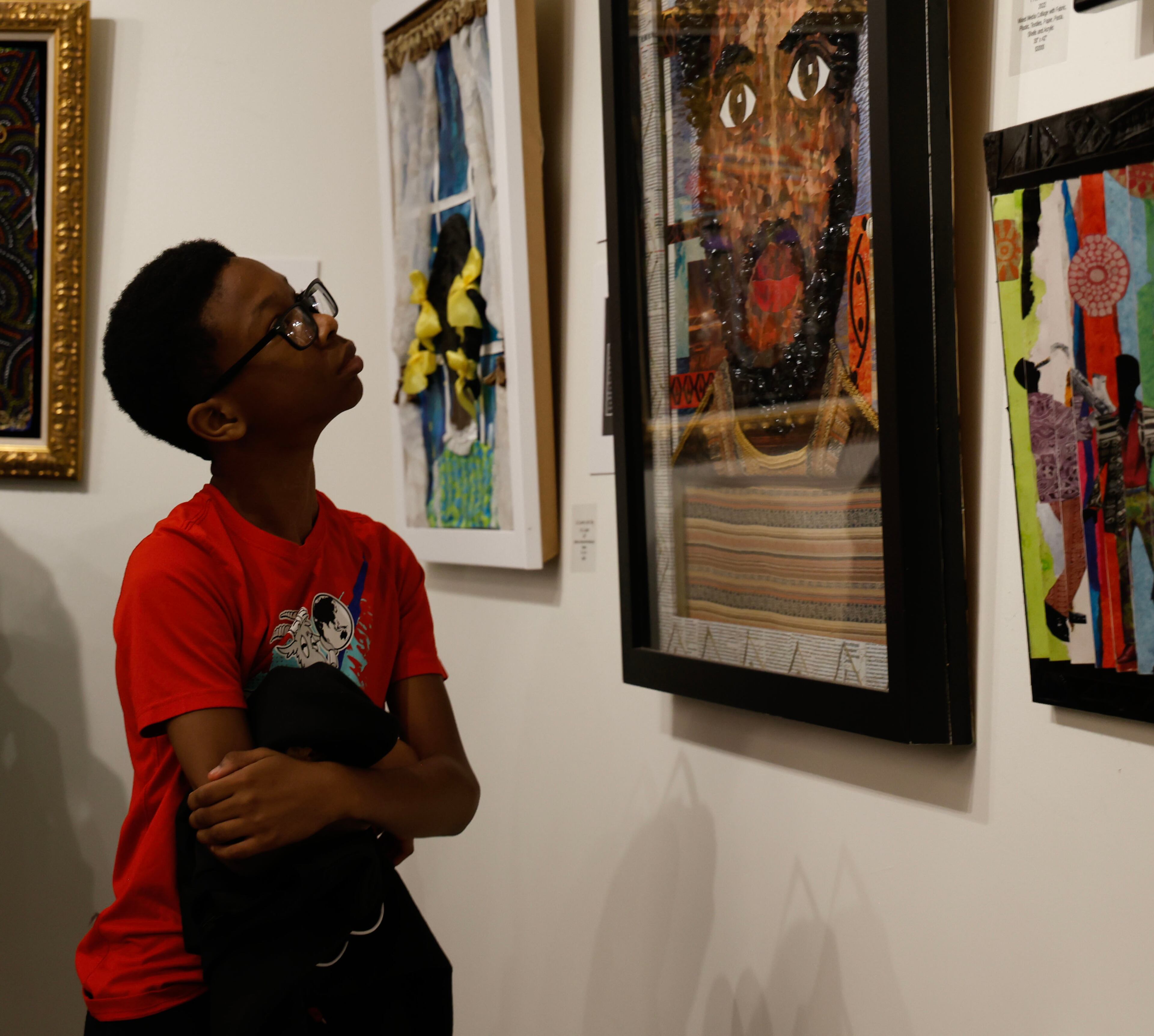 Mason Harris, 11, intently studies the work of artist J. Stacey Grayson at his opening art exhibition at the Fulton County Central Library. Saturday, November 8, 2025. (Akili-Casundria Ramsess, EyeAkili Media for the AJC)