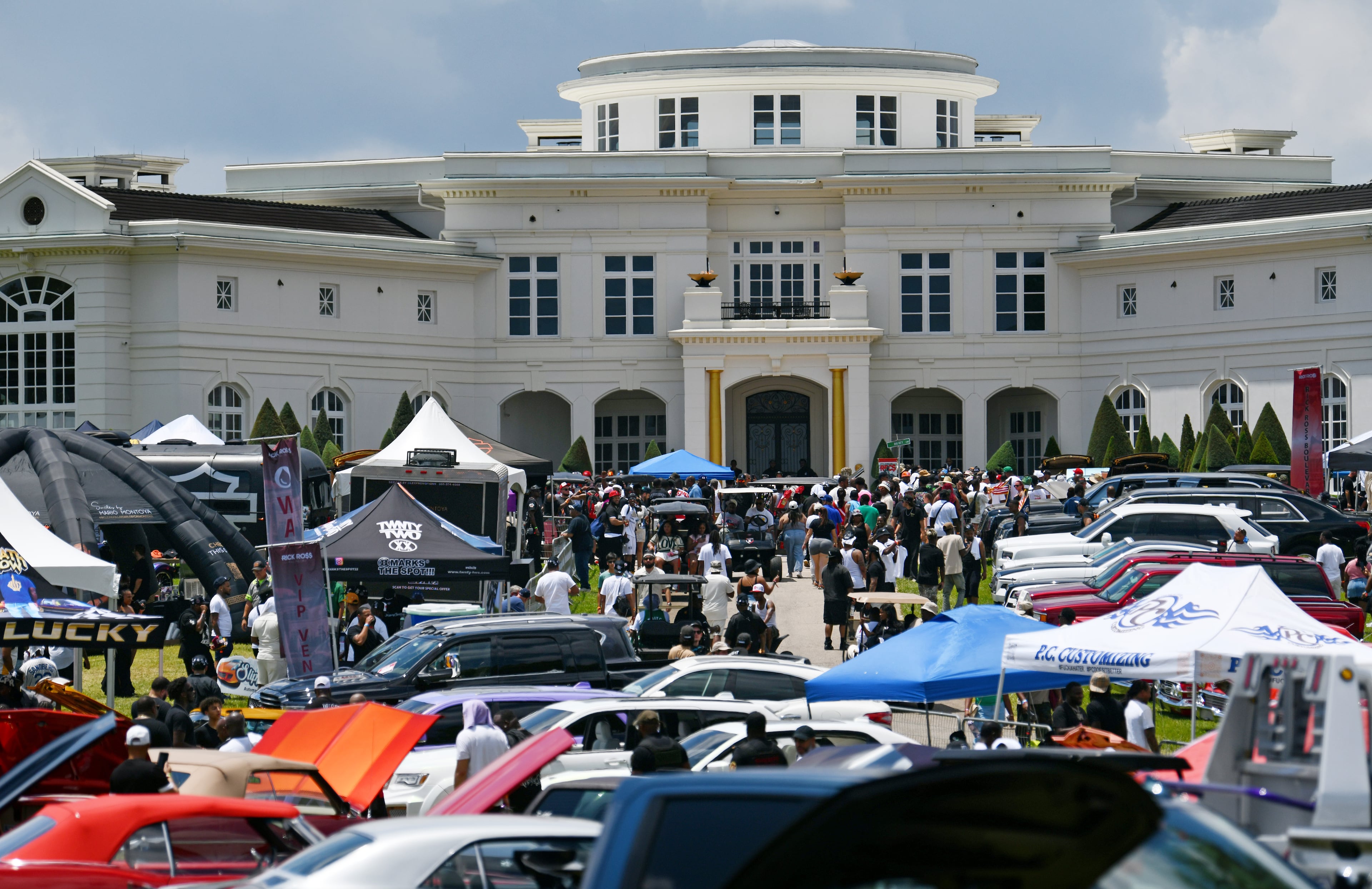 Attendees walk through rows of classic/custom automobiles, luxury vehicles, boats, RVs and trailers on the front lawn of rapper Rick Ross's mansion during the fourth annual Rick Ross Car and Bike Show on Saturday in Fayetteville. (Hyosub Shin/AJC)