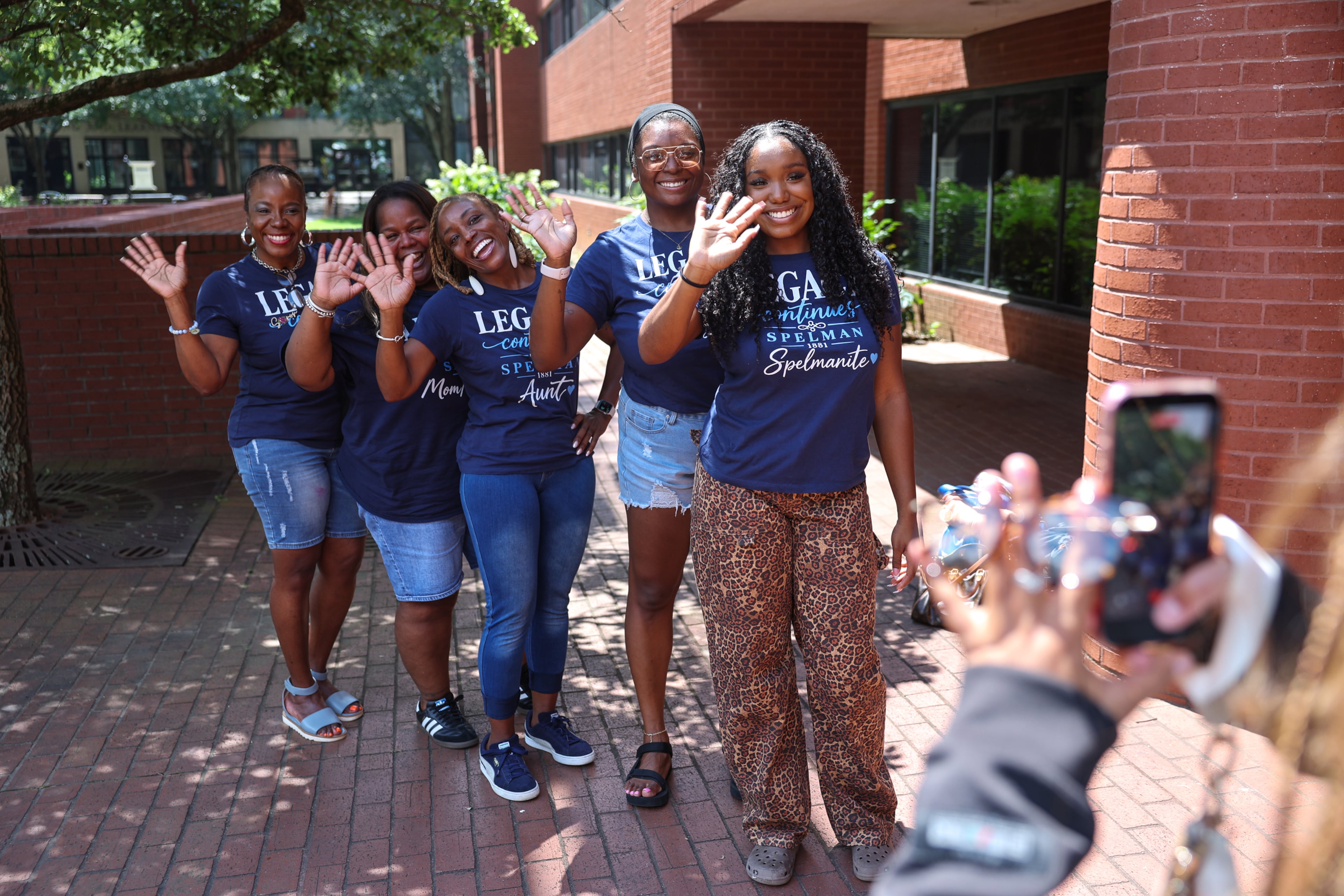(R-L) First-year honors student Brooke Spiva along with alumnae sister Gabbie Moore, aunt Tenaya Watson, godmother Shaunté Parker and mother Yolanda Watson Spiva, wave for a social media video in front of The Donald and Isabel Stewart Living-Learning Center at Spelman College in Atlanta on Aug. 11, 2026. (Arvin Temkar/AJC)