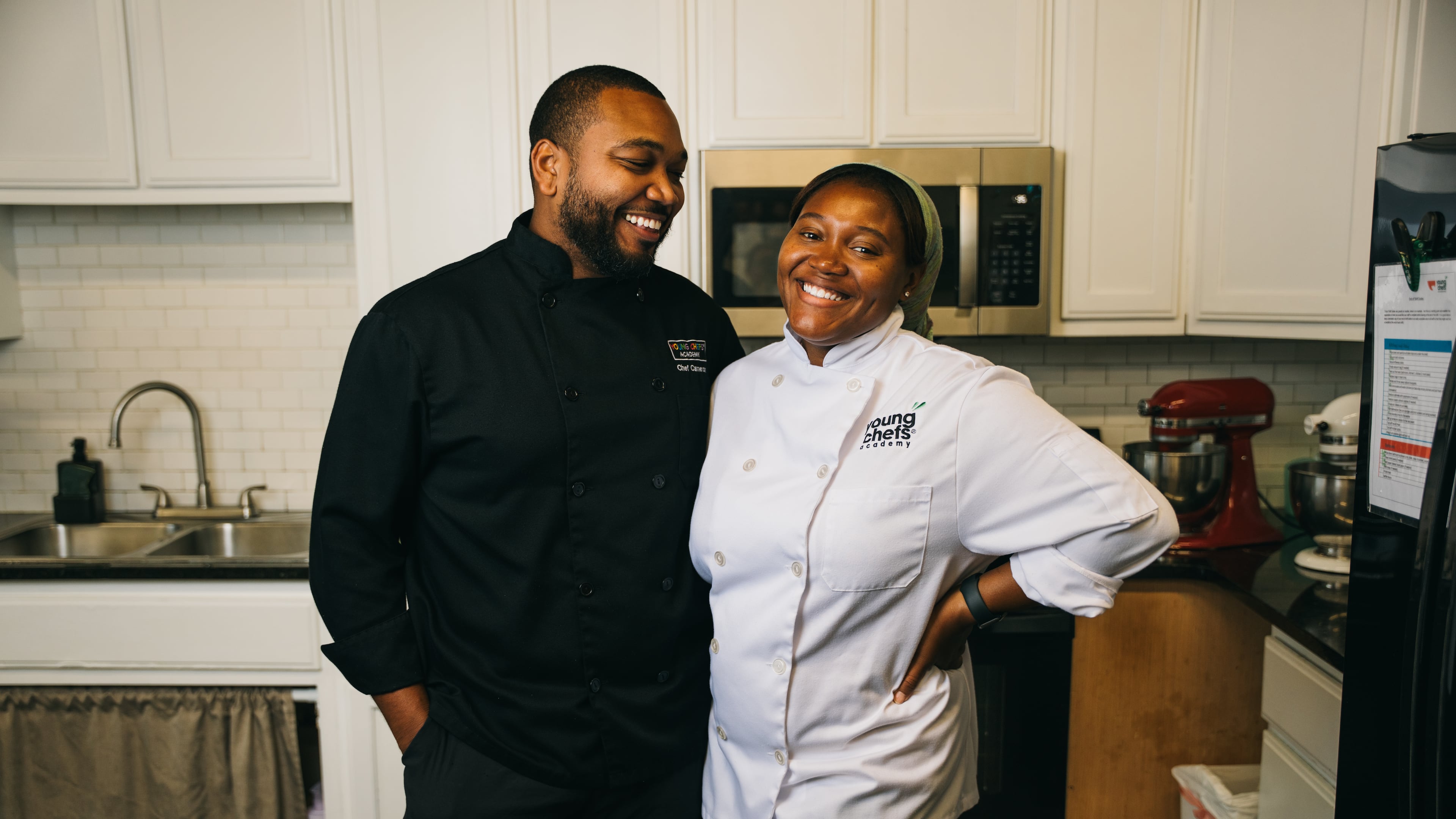 Married chefs Cameron Williams, left, and Arielle Jolly-Williams, right, pose for a portrait in their Young Chefs Academy kitchen in Sandy Springs, Georgia, on Friday, Aug. 28, 2026. (Olivia Bowdoin for the AJC)