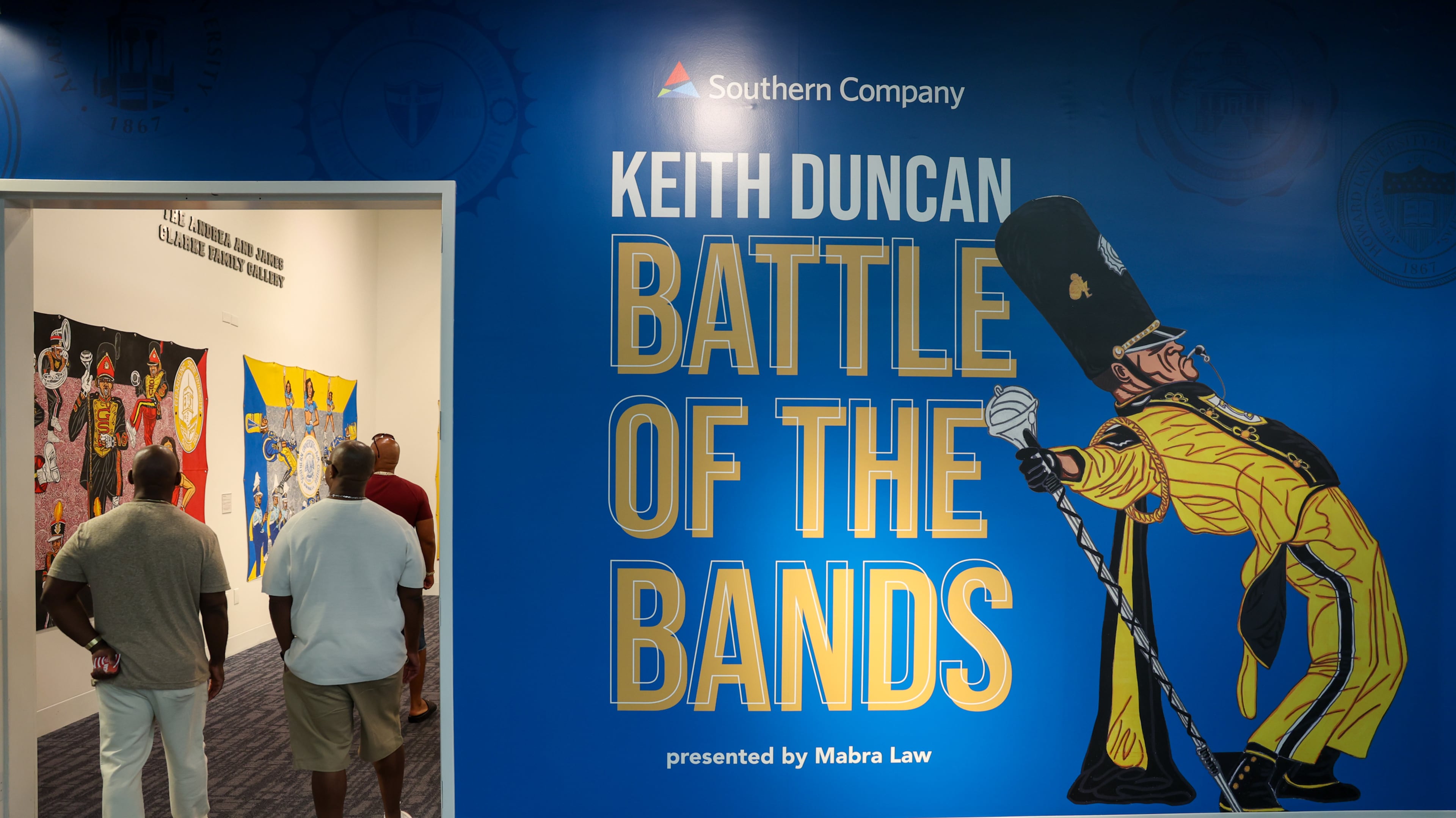 Visitors view artist Keith Duncan’s exhibit “Battle of the Bands,” inspired by HBCU band culture, at the College Football Hall of Fame in Atlanta on Sept. 11, 2026. Duncan utilizes bright colors to convey the competition and pageantry between the bands. (Arvin Temkar/AJC)