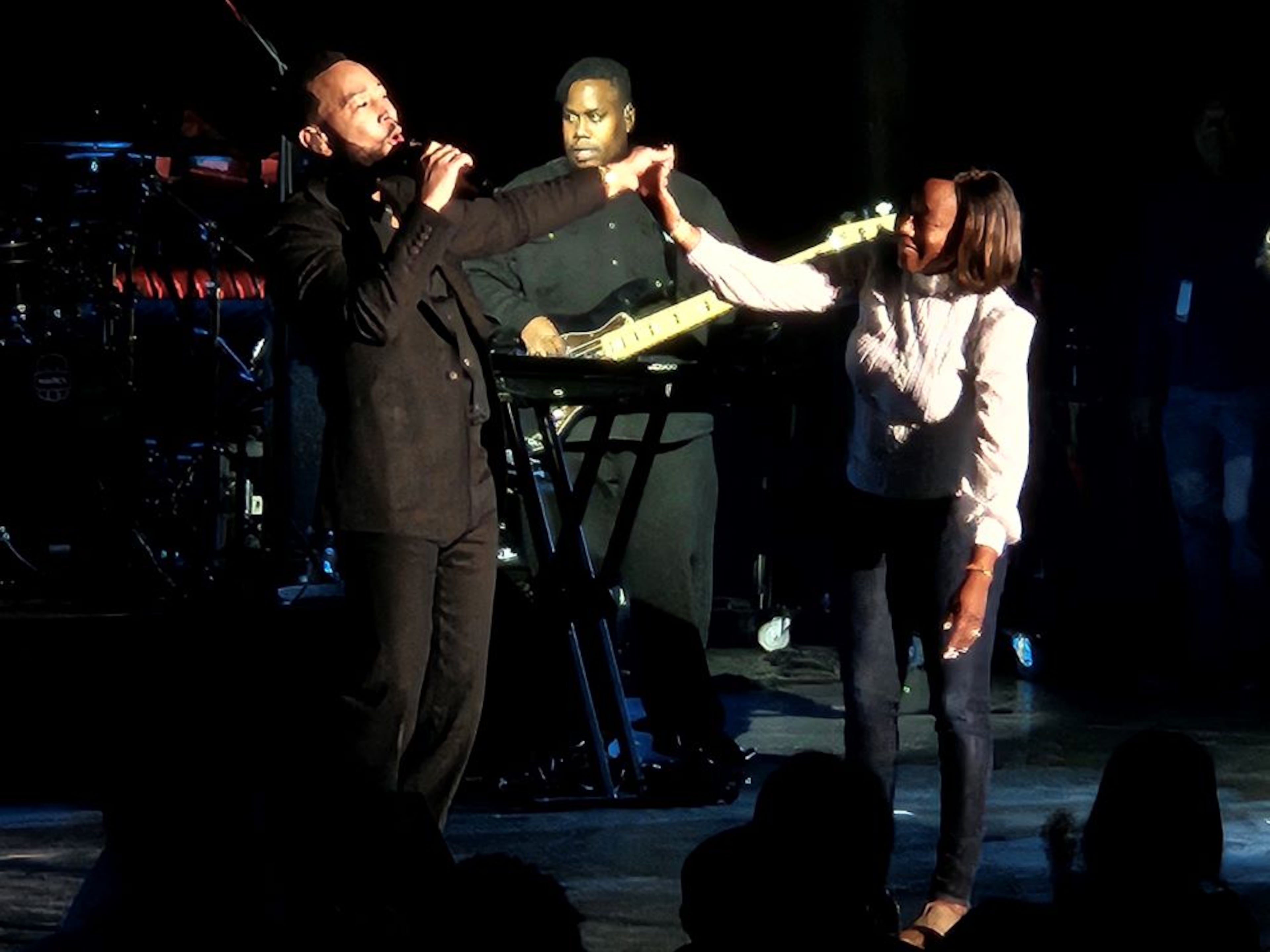Singer John Legend pulls a fan from the audience onstage during a performance of “Slow Dance” at Synovus Bank Amphitheater at Chastain Park on Friday, Oct. 24, 2025, in Atlanta. (Christopher Daniel/AJC)