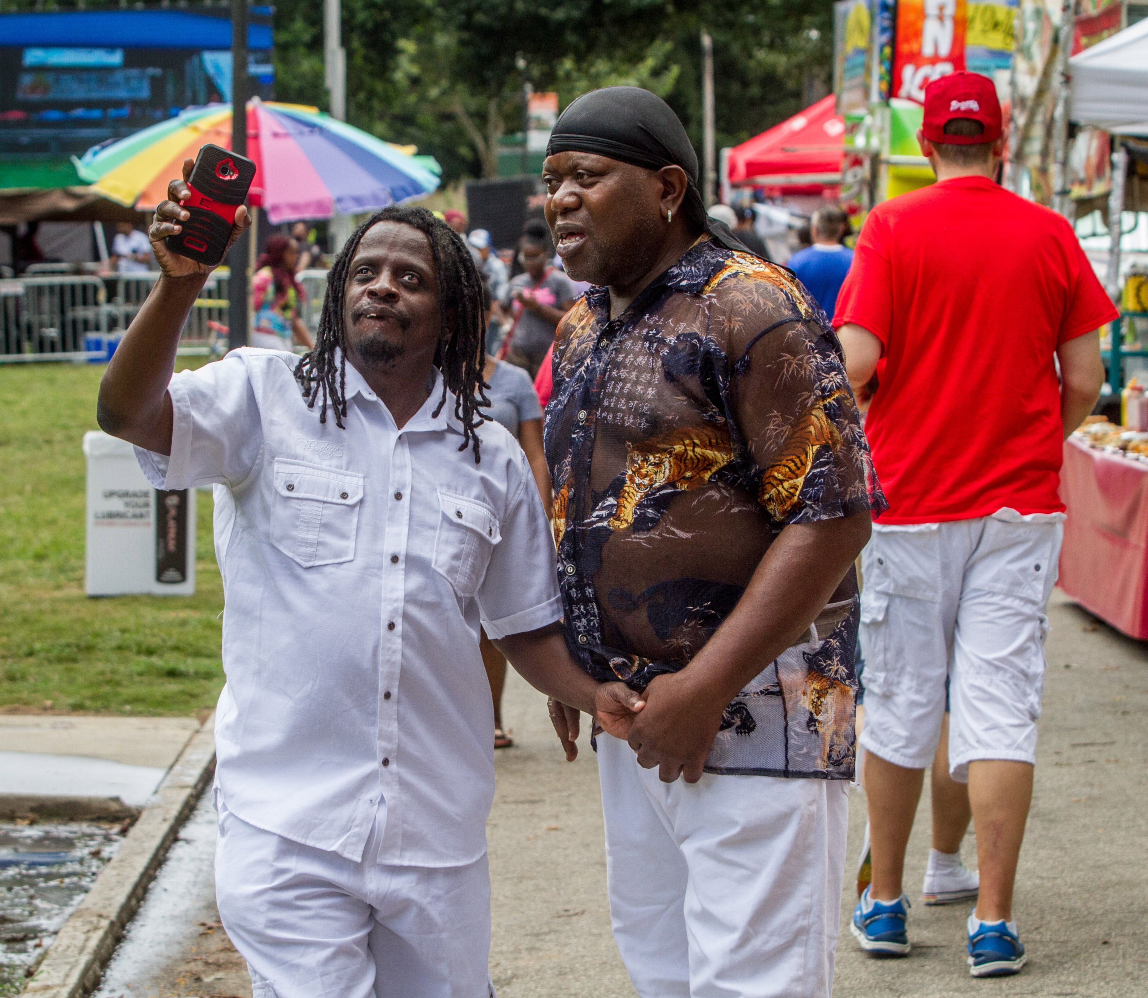 Eddie Bell (left) and John Wade stream the announcement of their engagement on Facebook Live during the Pure Heat Community Festival in Piedmont Park on Sunday, Sept. 2, 2018. The Atlanta Black Pride Weekend is considered the largest celebration of its kind. (Steve Schaefer for the AJC)