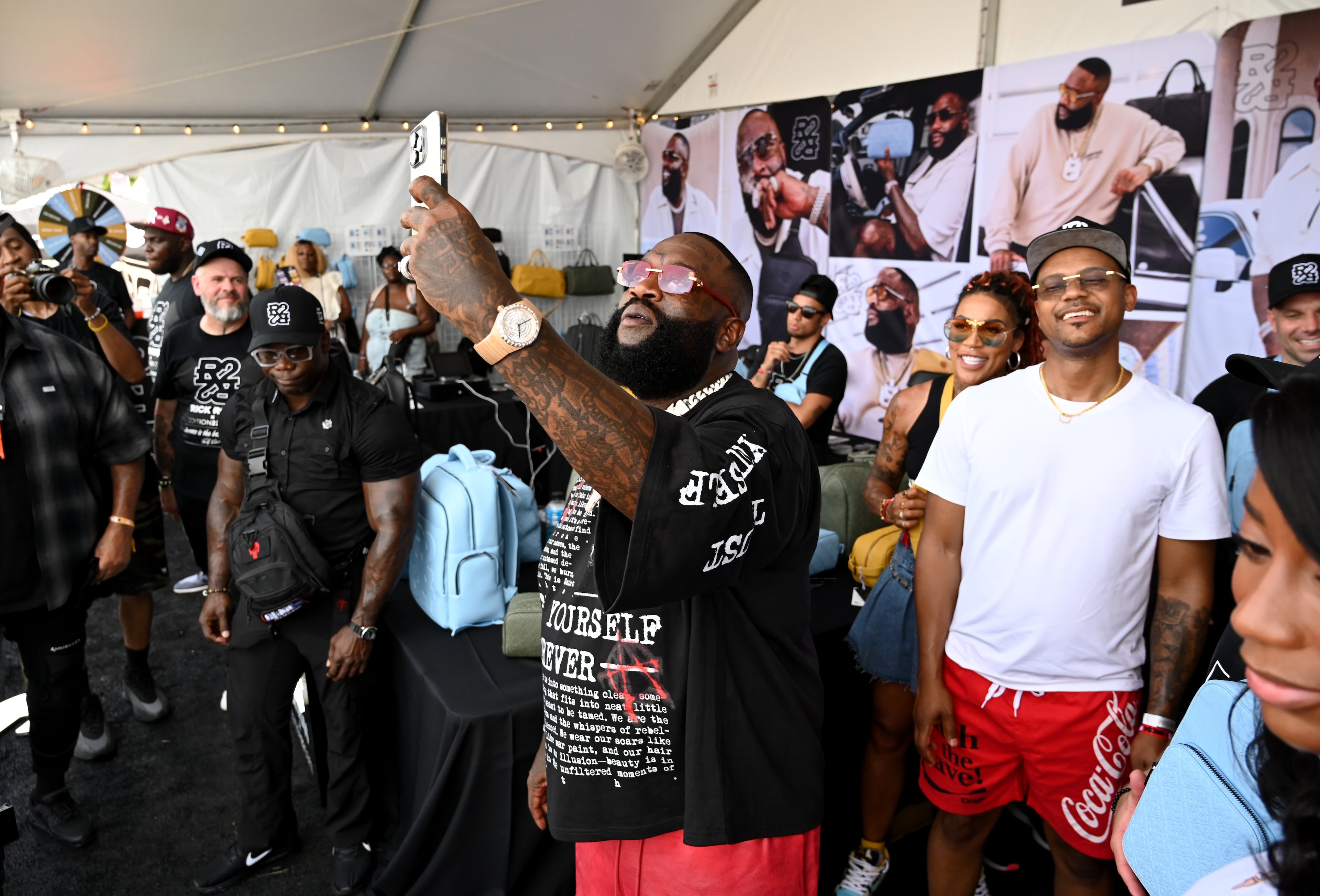 Rick Ross takes a selfie as he visits the vendor selling his luxury bag collection with Real Edition 22 during the Rick Ross Car Show on Saturday in Fayetteville. (Hyosub Shin/AJC)
