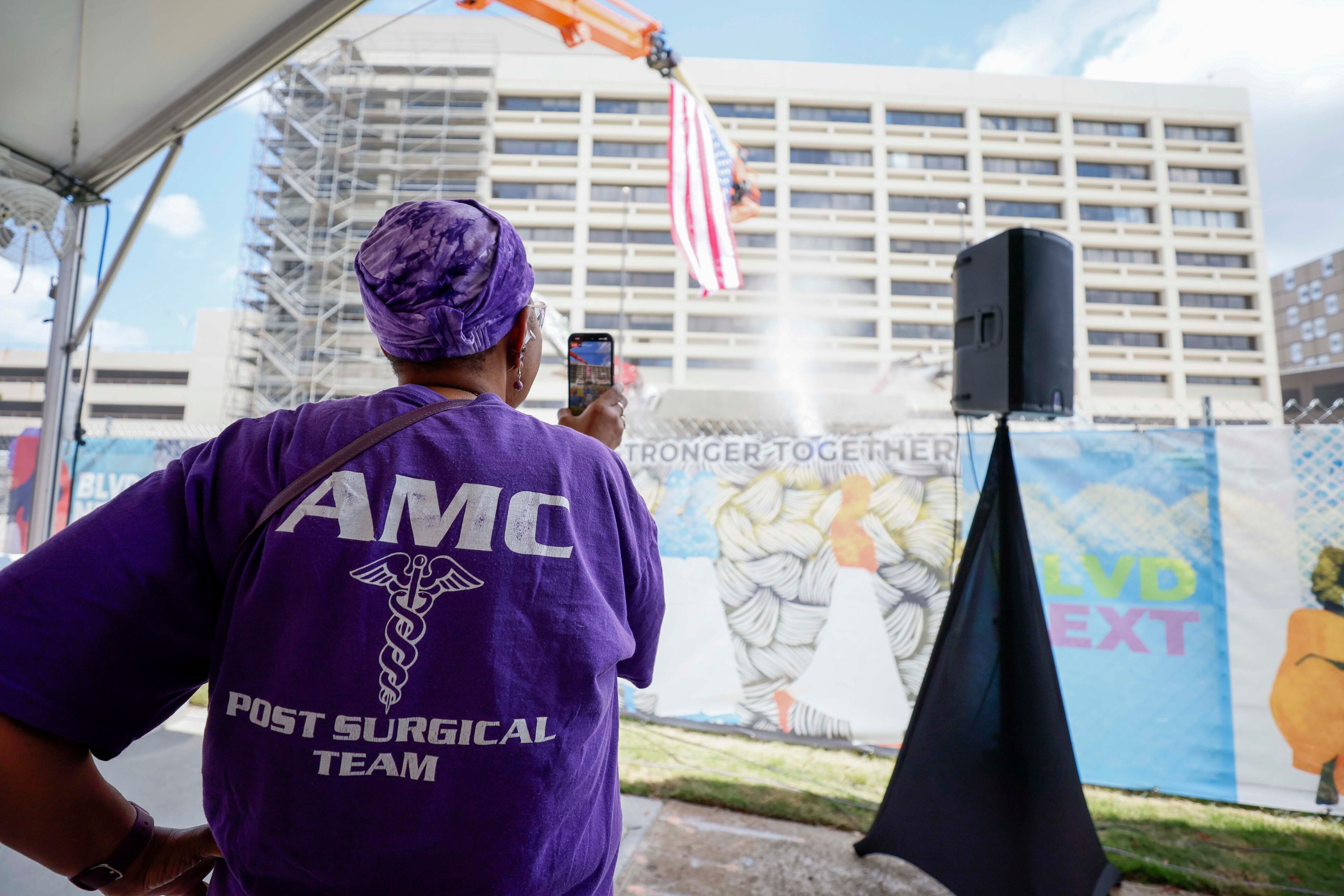 Former Atlanta Medical Center administrator secretary Meta Anthony records a video as heavy equipment begins demolishing the site, marking the start of the project's transformation into a new phase on Monday, June 30, 2025. The AMC served the surrounding communities for over a century. (Miguel Martinez/AJC)