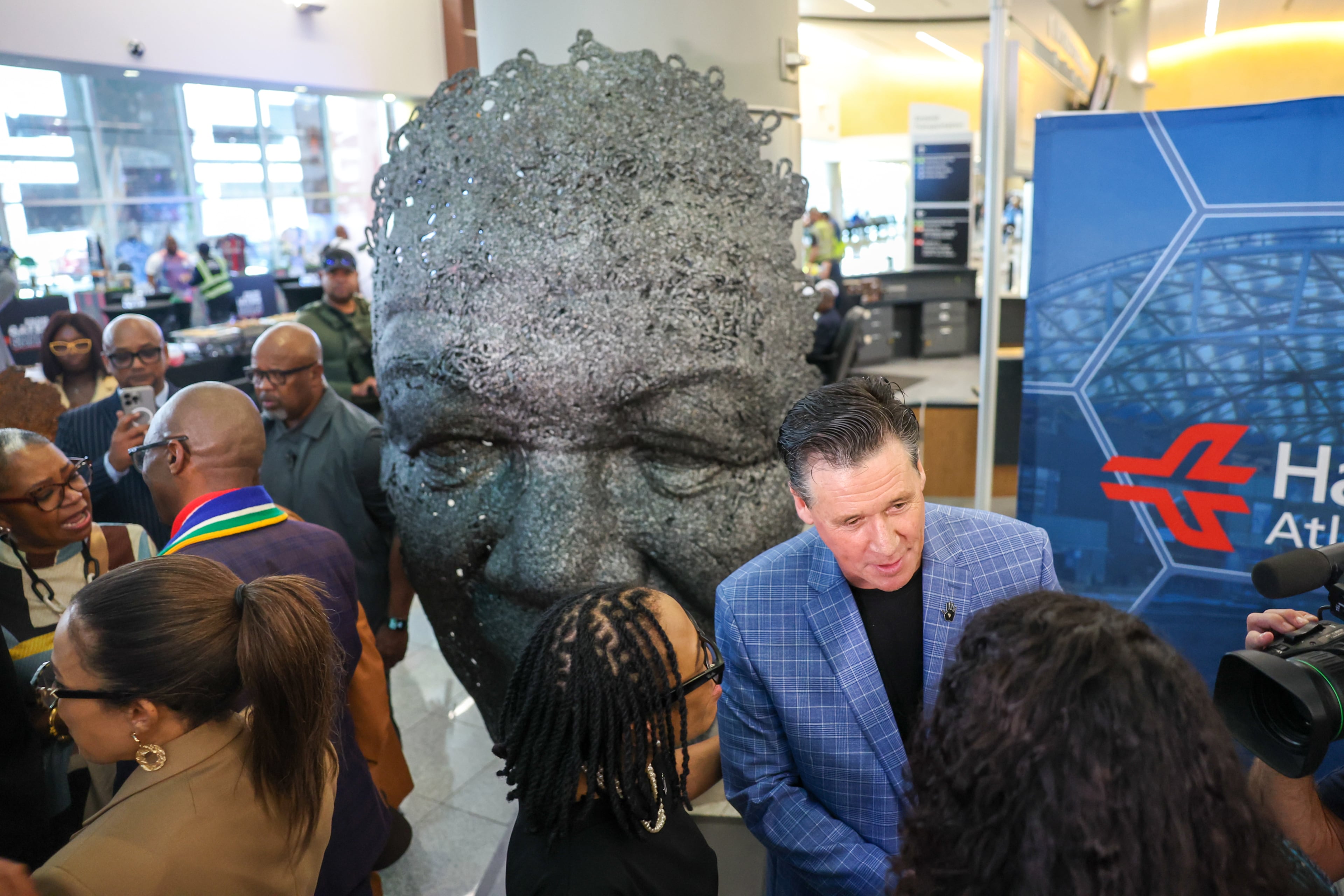 Sculptor Marco Olivier (center right) speaks to guests at a ceremony unveiling his Nelson Mandela sculpture in the international terminal at Hartsfield-Jackson Atlanta International Airport on Wednesday, May 27, 2026. (Arvin Temkar/AJC)