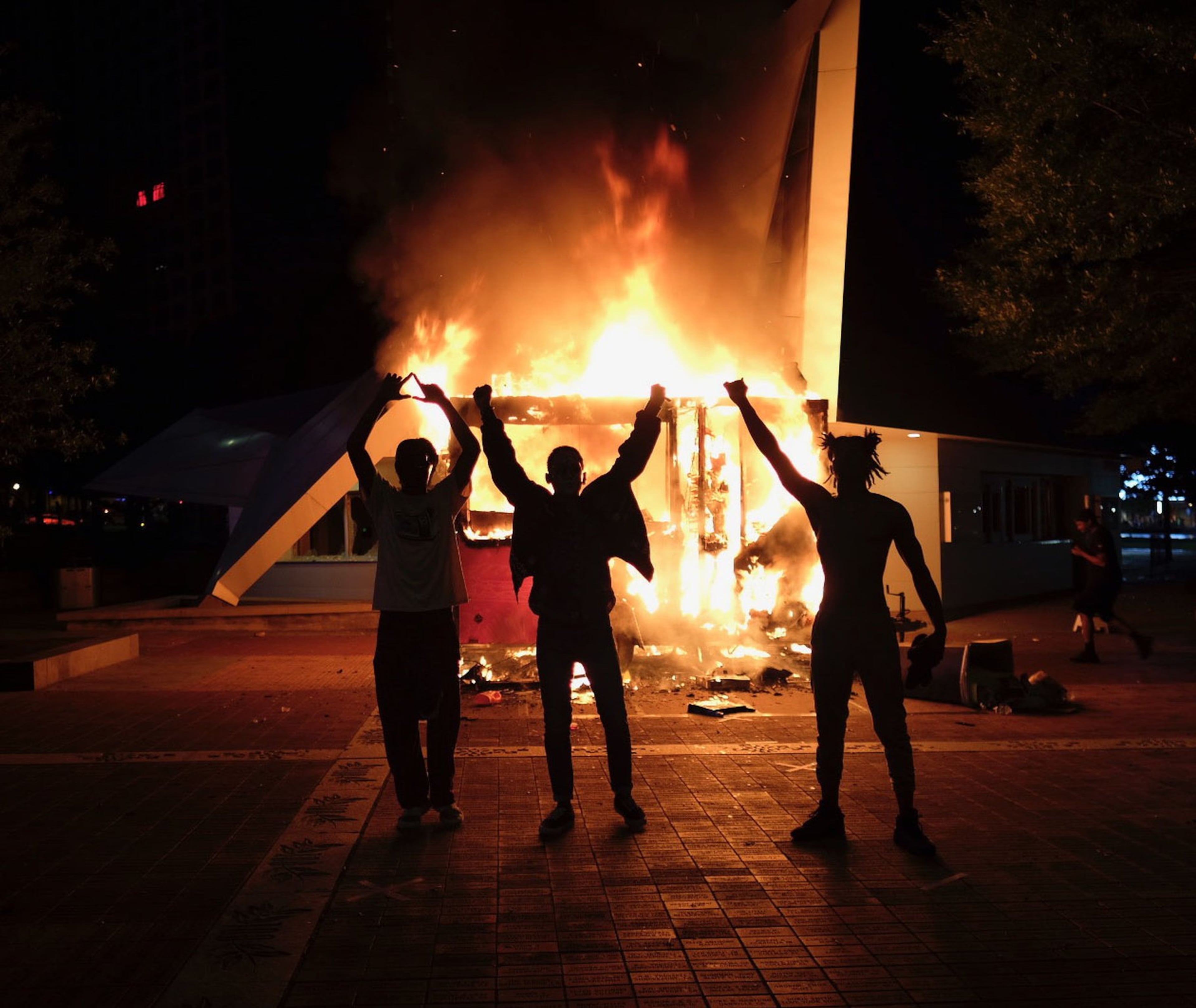Protesters in front of a burning vendor cart outside the visitor bureau office in Centennial Park. After a peaceful march to the Georgia State Capitol that swelled into the hundreds, protestors returned to the area around the Centennial Olympic Park and CNN Center, where some confronted police, who sprayed some demonstrators with pepper spray. They carried signs and chanted their messages of outrage over the death of George Floyd in Minneapolis. (Ben Gray for the AJC)