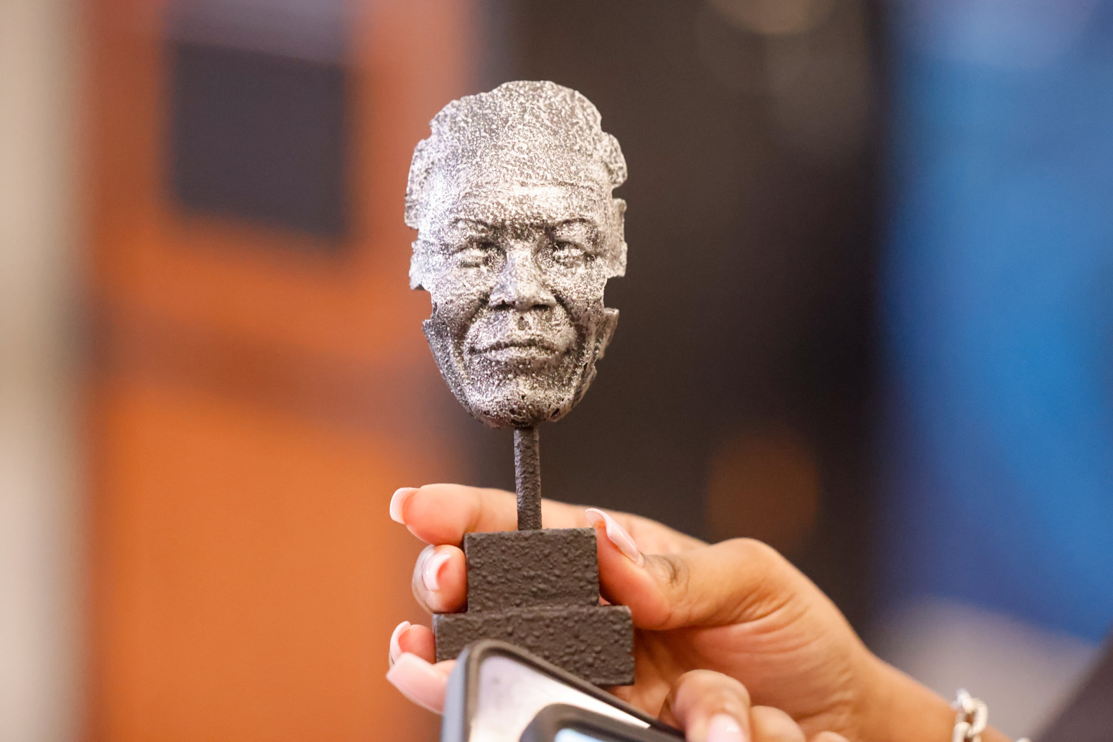 An attendee holds a small version of the Nelson Mandela statue that was unveiled at Hartsfield-Jackson Atlanta International Airport on Wednesday, May 27, 2026. (Arvin Temkar/AJC)