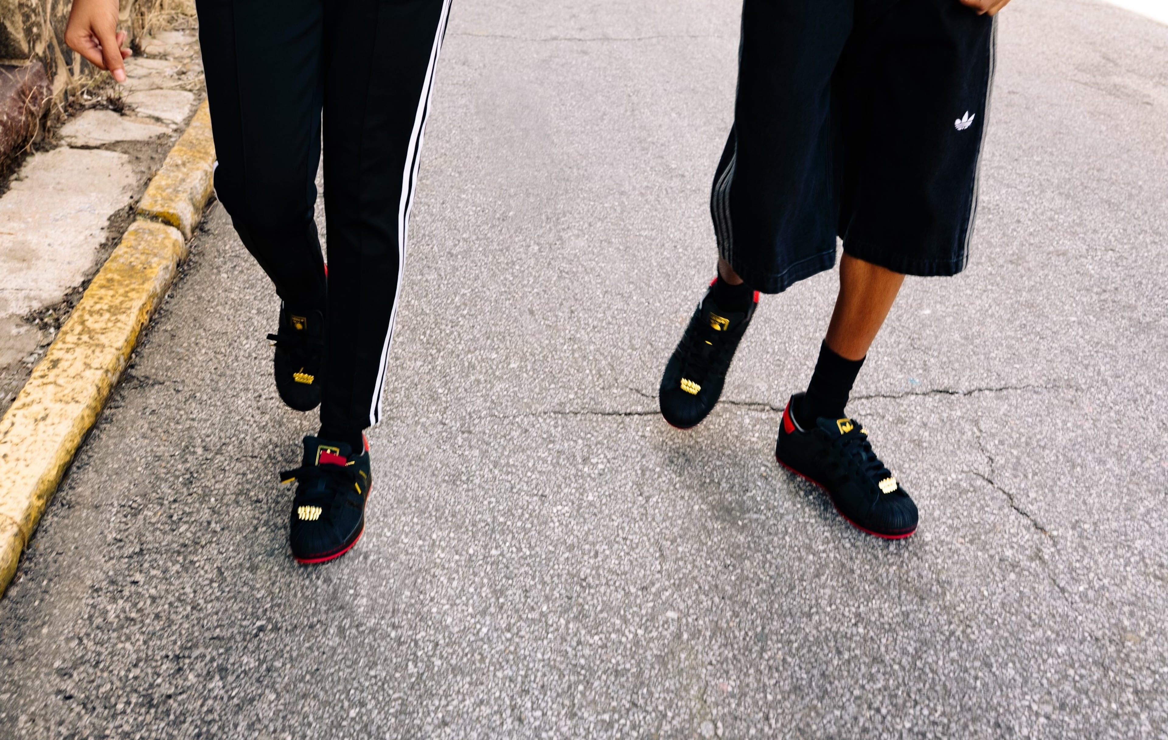 Two models wear the 2025 limited-edition "404 Day!" sneaker, created in collaboration with the 404 Collective, The Athlete's Foot and Adidas. A lace lock on the front of each shoe was created to resemble gold teeth.
