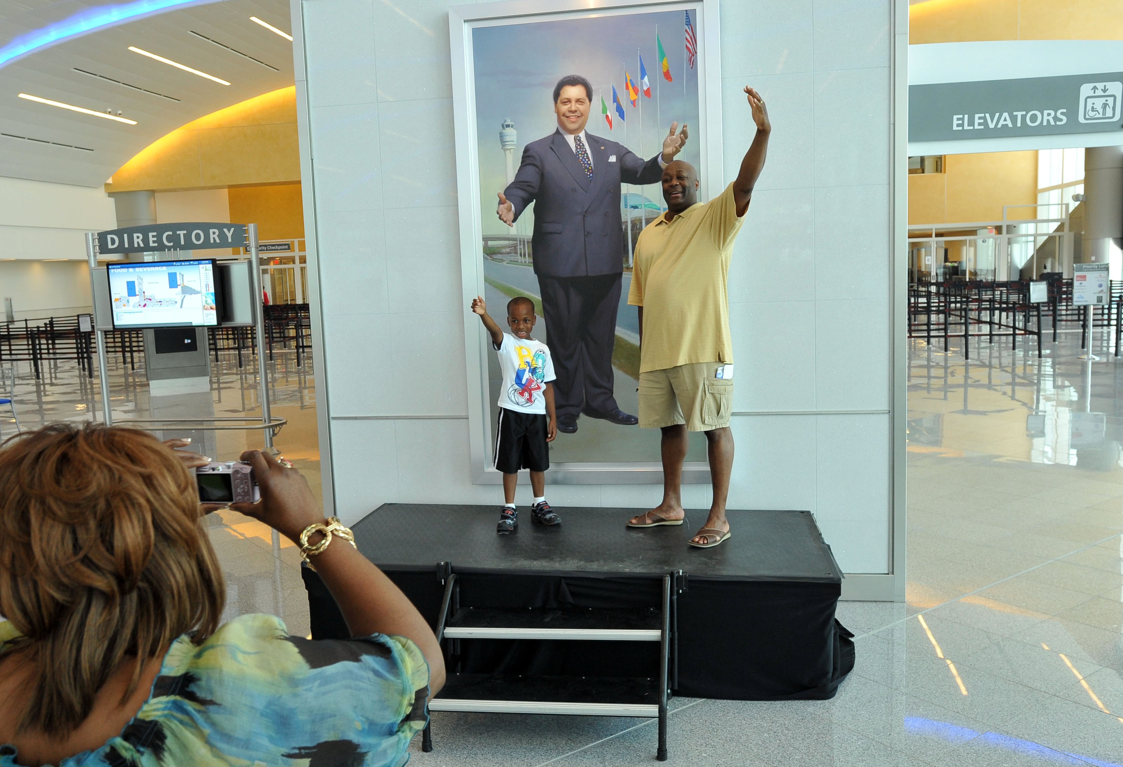 Glenn Thomas (right), of Lithonia, and his 6-year-old son Myles pose in front of Maynard H. Jackson Jr.'s portrait as Hartsfield-Jackson Atlanta International Airport staffer Myrna White takes a picture during an open house at Maynard H. Jackson Jr. International Terminal in Atlanta on Saturday, May 5, 2012. The new terminal honors the late mayor, who was instrumental in turning Atlanta into a major international air hub. (AJC file photo)