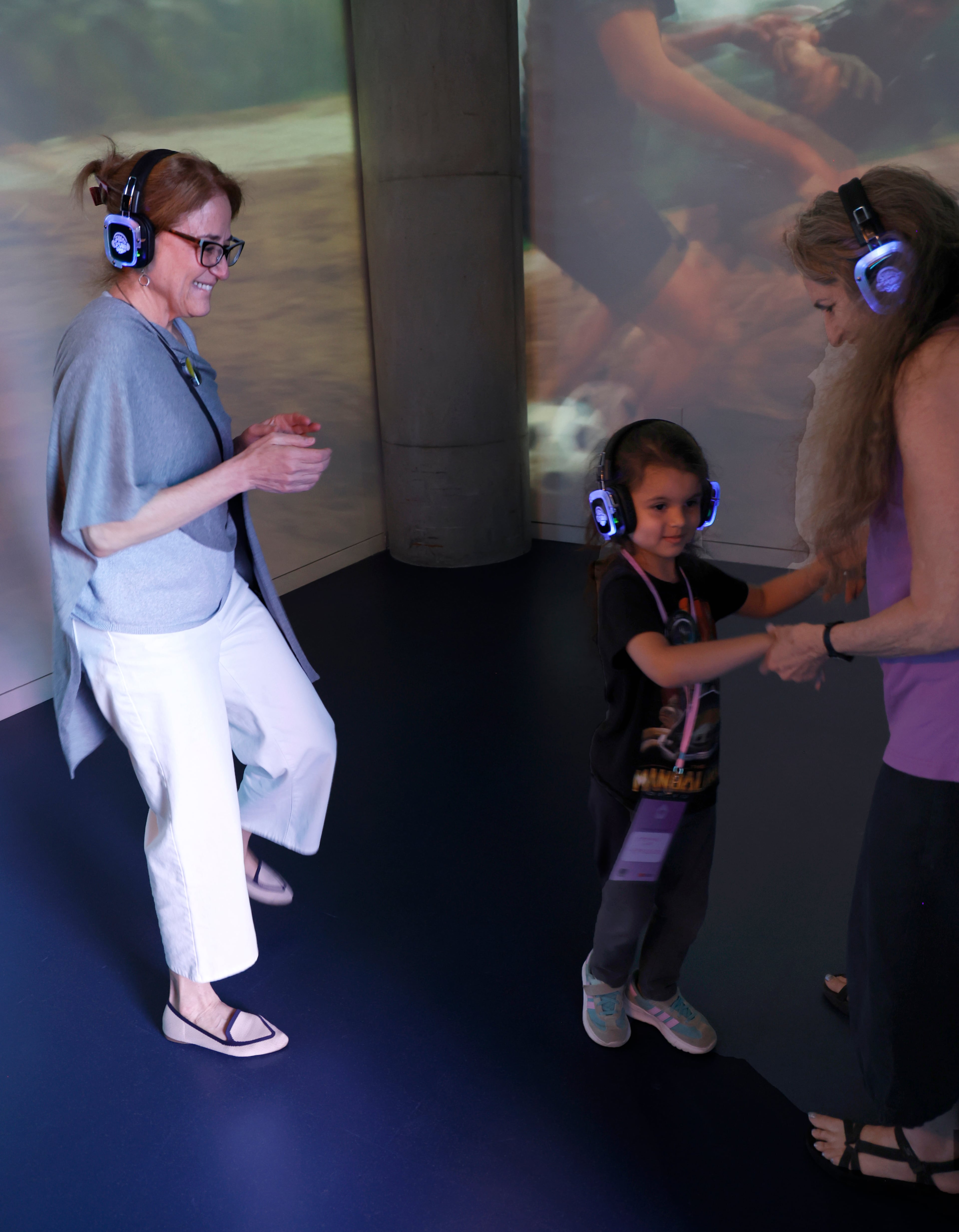 Jill Savitt, leader of the National Center for Civil and Human Rights, dances along with McKenzie Luse, 4, and her grandmother, Maria Saporta, as they listen through headphones to songs popular in the Black Power Movement at the juke box in the Change Agent Adventure: Children’s Gallery. (Akili-Casundria Ramsess/EyeAkili Media)