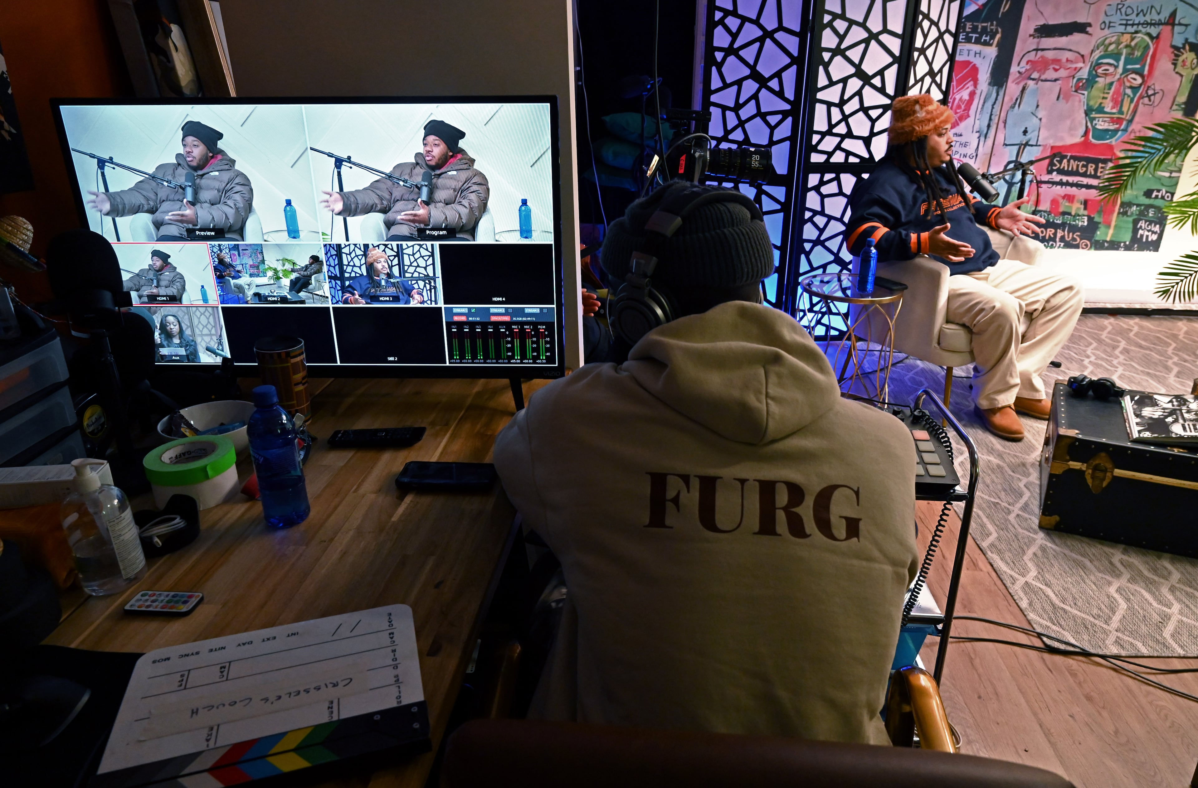 Podcaster Deante' Kyle (right, in background) records "Grits & Eggs" with rapper LaRussell in recording studio Saturday, Jan. 31, 2026, in Atlanta. (Hyosub Shin/AJC)