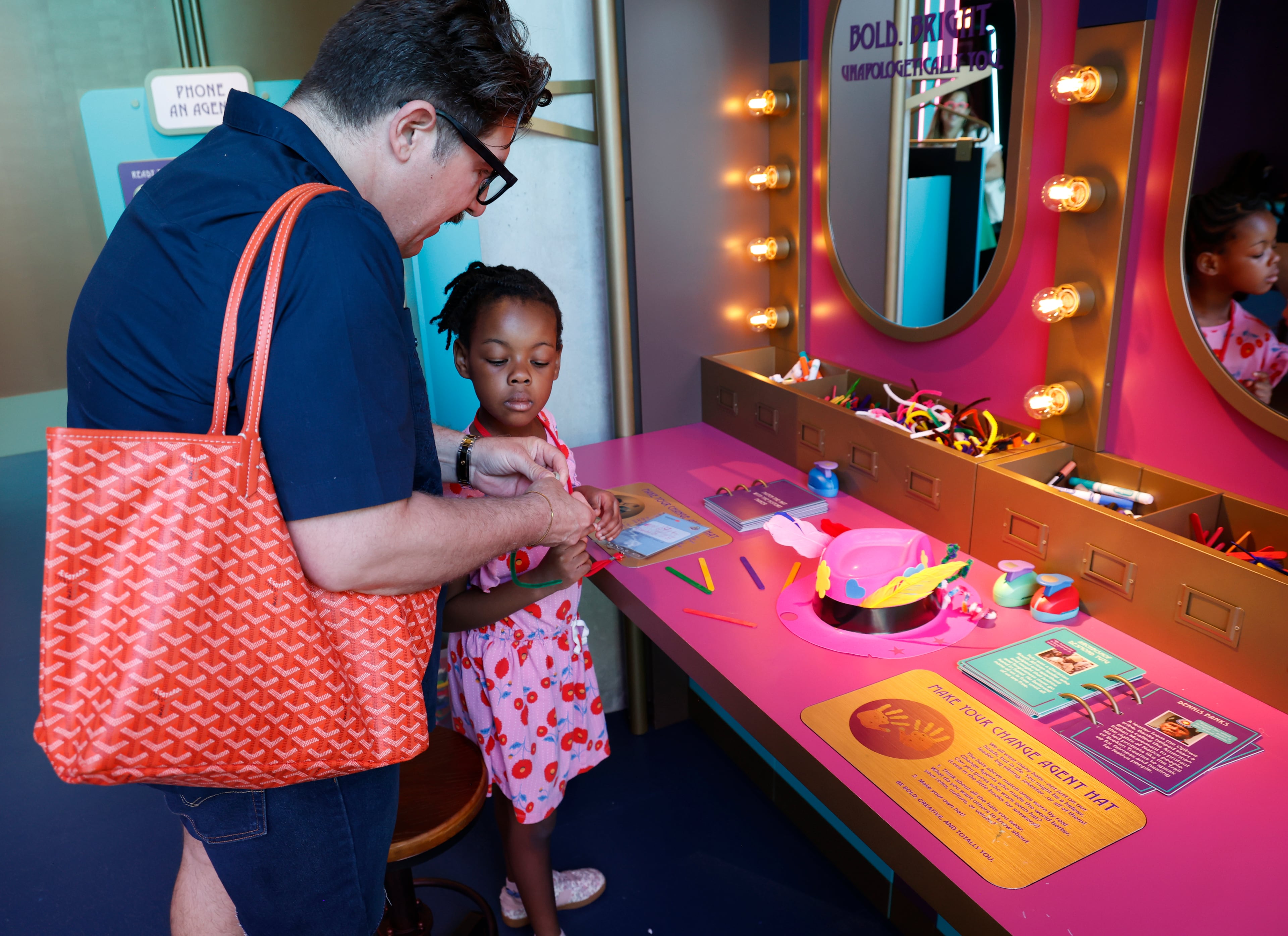 Mike Szott with his daughter Jackie Bresnahan, 5, as she makes a string for her badge and begins creating a hat at a preview of the National Center for Civil and Human Rights’ Change Agent Adventure: Children’s Gallery. (Akili-Casundria Ramsess/EyeAkili Media)
