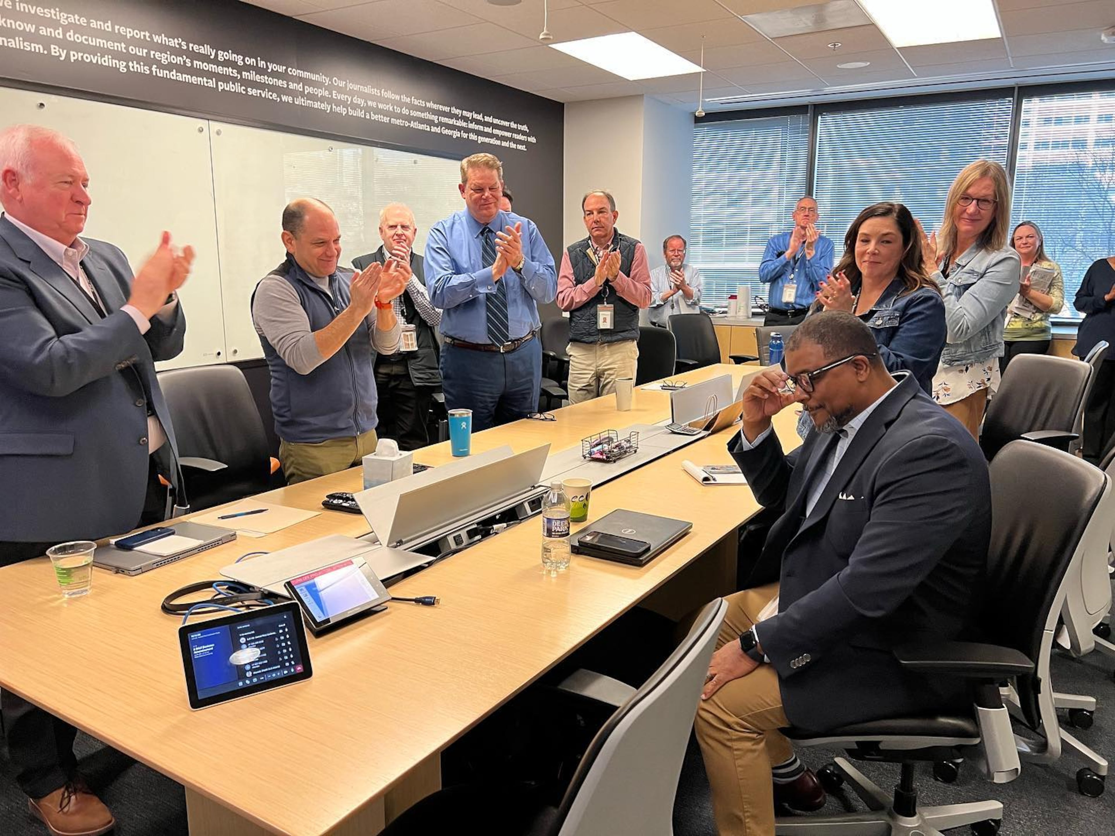 Leroy Chapman (sitting) gets a standing ovation after it was announced he would be the AJC's new editor-in-chief. (Courtesy of Ryon Horne)