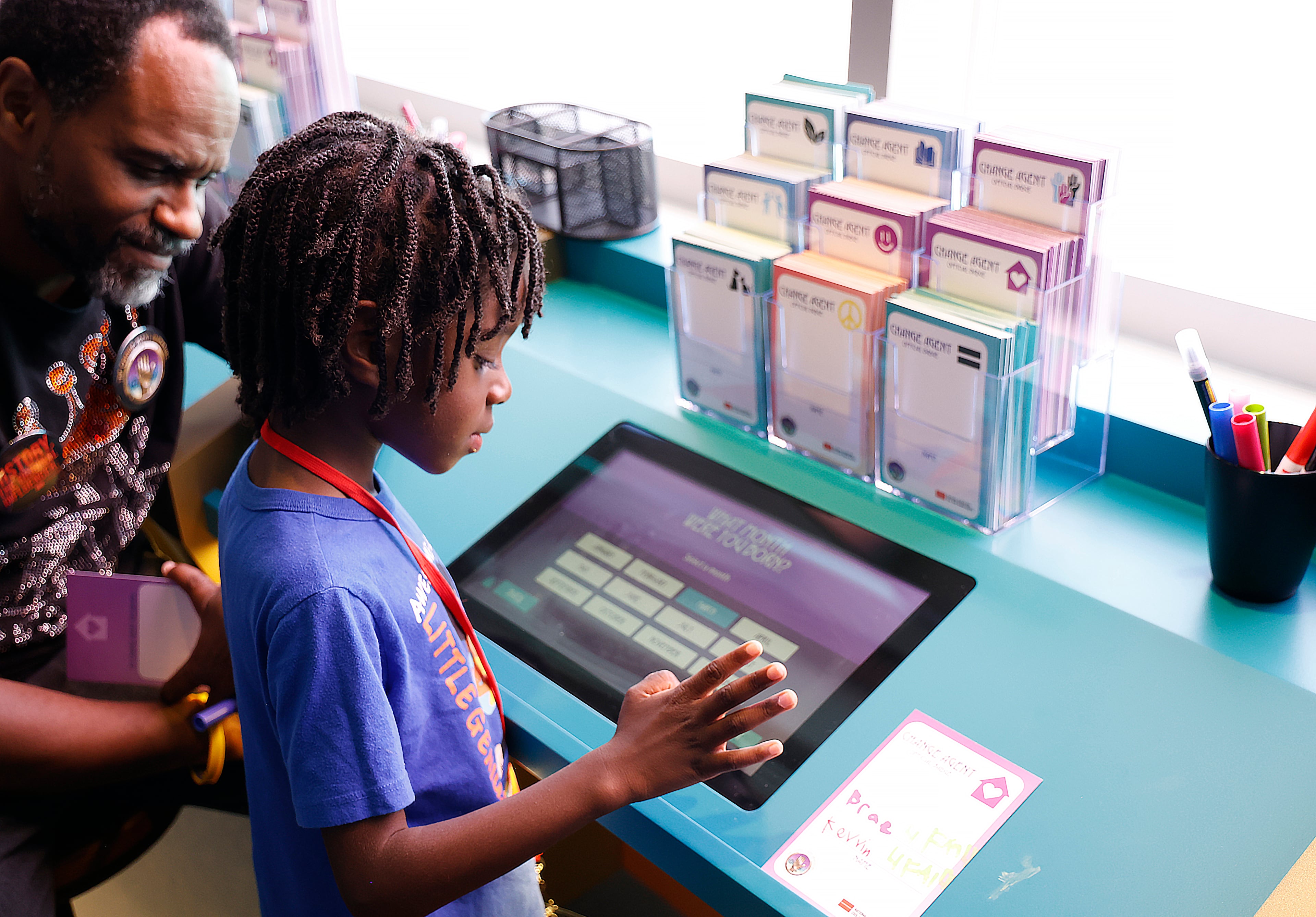 Kevvin Hankins Jr. makes a badge as his dad, Kevvin Hankins Sr., looks on. (Akili-Casundria Ramsess/EyeAkili Media)