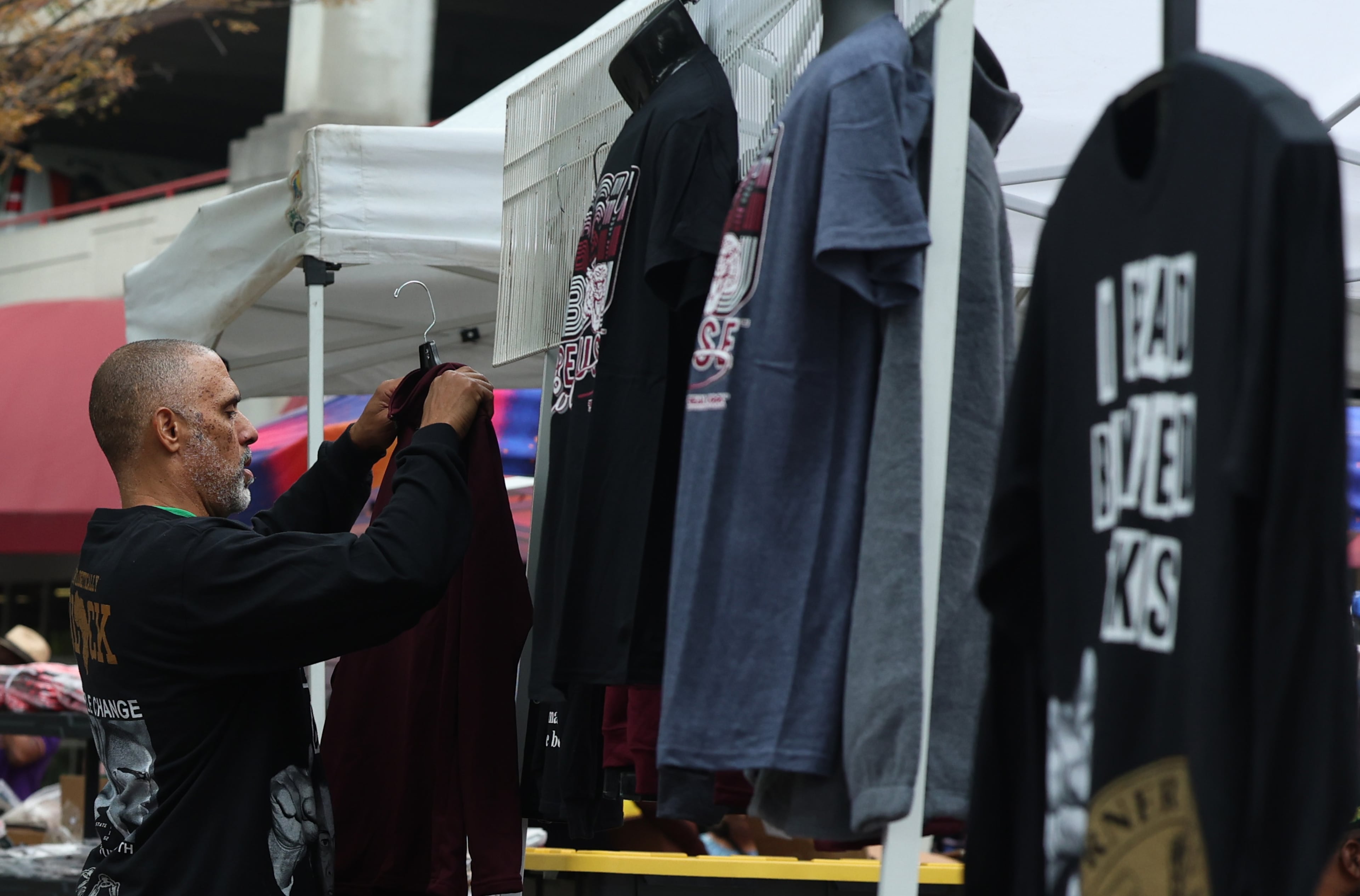 Clothing vendor Steve Payne sets up his custom designs at the Morehouse homecoming. He is an alum of Morehouse, class of 1990 and has been attending the homecoming event for 31 years. (Akili-Casundria Ramsess, EyeAkili Media for the AJC 2025)