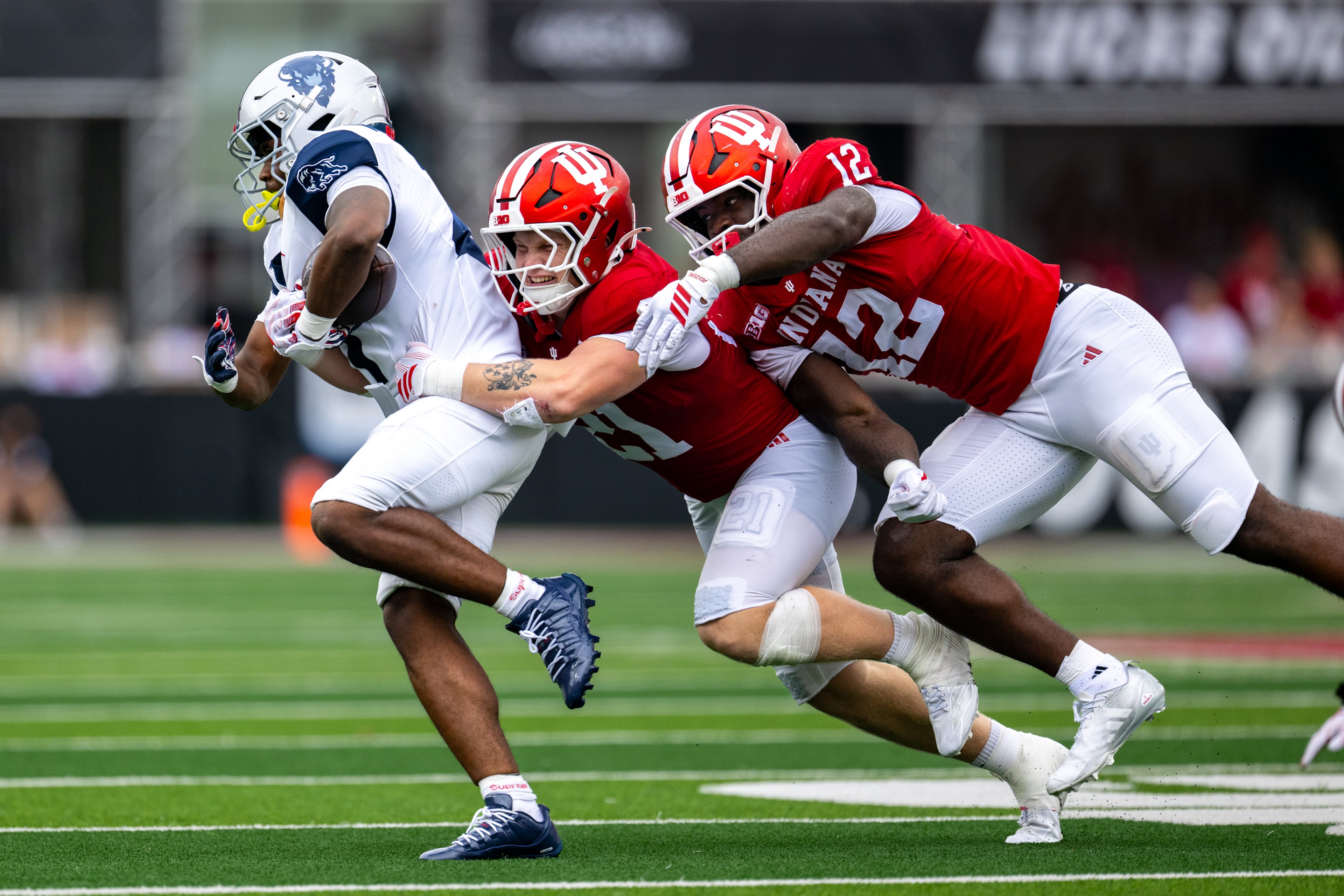 Howard running back John Washington IIl (left) is contacted by Indiana linebacker Jacob Savage (center) and defensive end Tobi Osunsanmi during the second half an NCAA college football game, Saturday, Sept. 12, 2026, in Bloomington, Ind. (Doug McSchooler/AP)