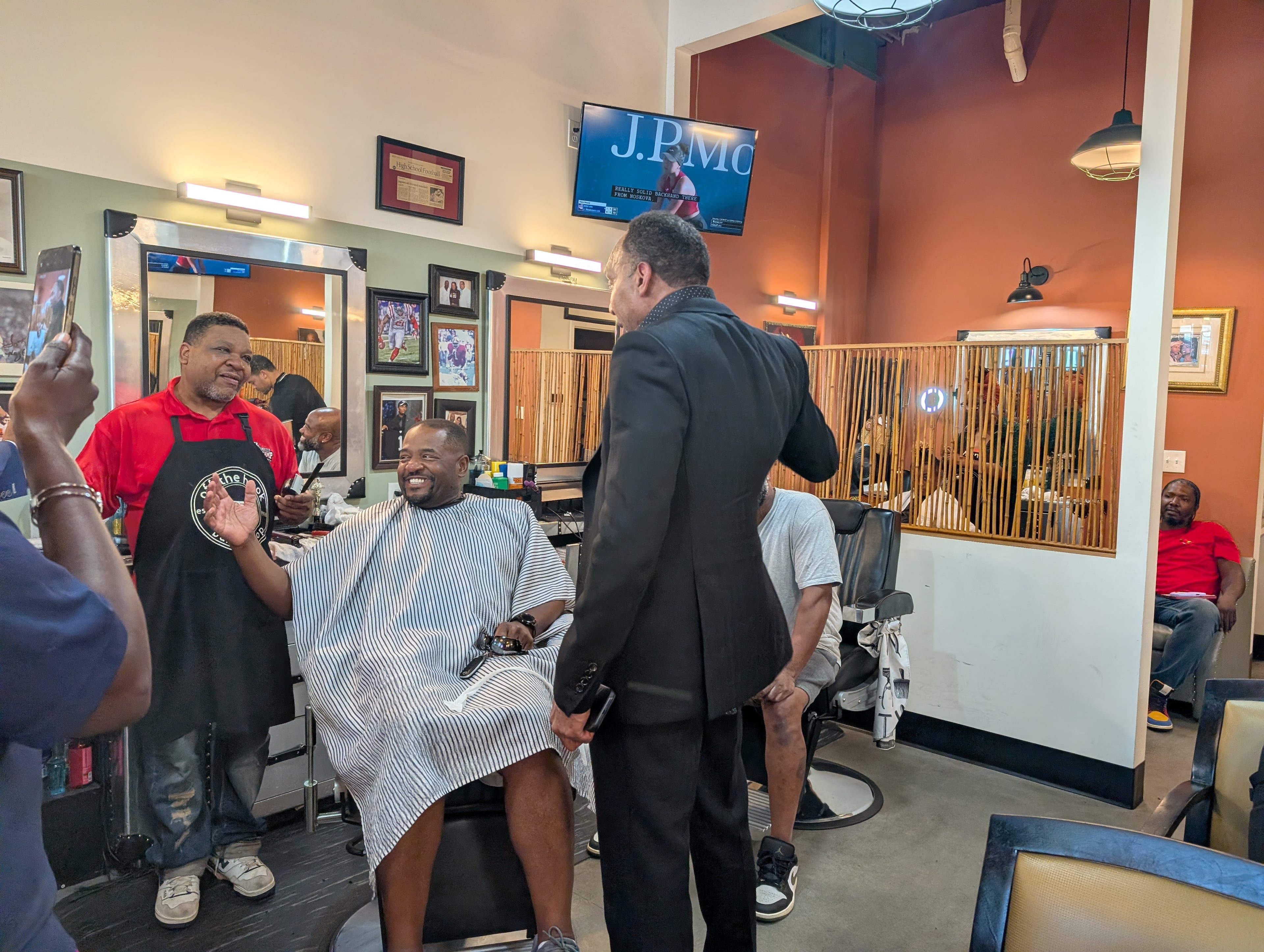 Stephen A. Smith (standing) laughs with former Atlanta City Council President Ceasar Mitchell, who is getting his hair cut. (Courtesy of A.R. Shaw)