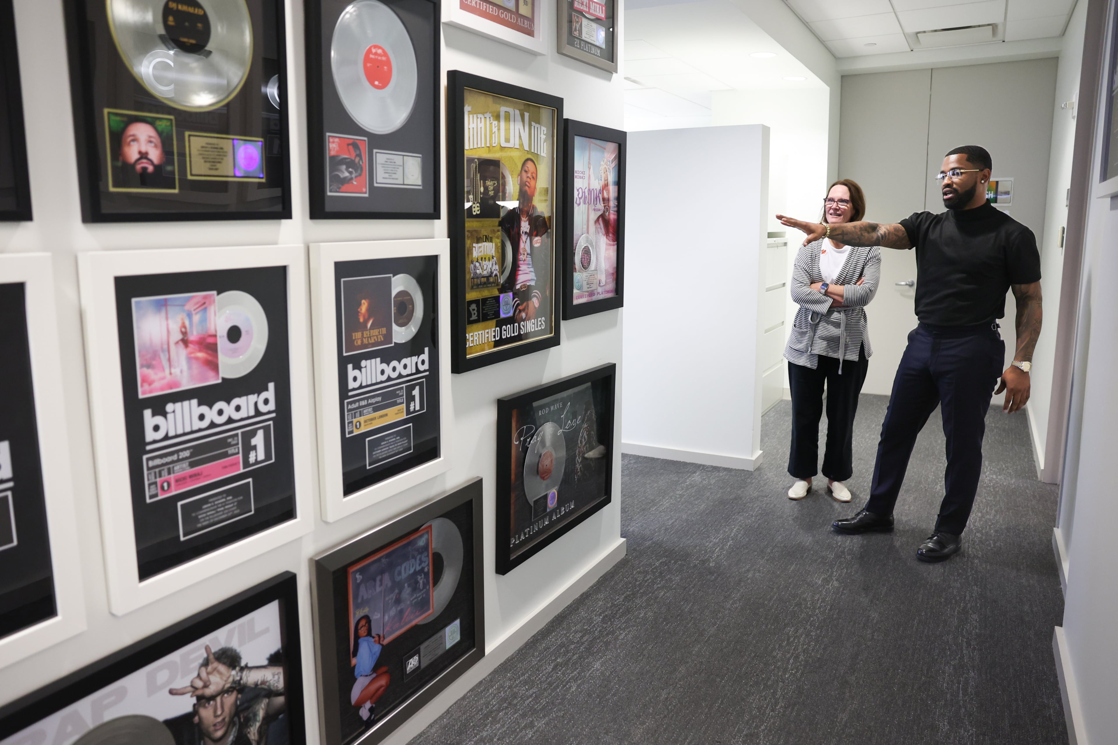 Atlanta-based entertainment attorney John Rose showcases a wall of hit records to managing partner Mary Barent Long at Fox Rothschild in Atlanta on June 16, 2026. Rose, 33, just became the youngest partner at Fox Rothschild. (Arvin Temkar/AJC)