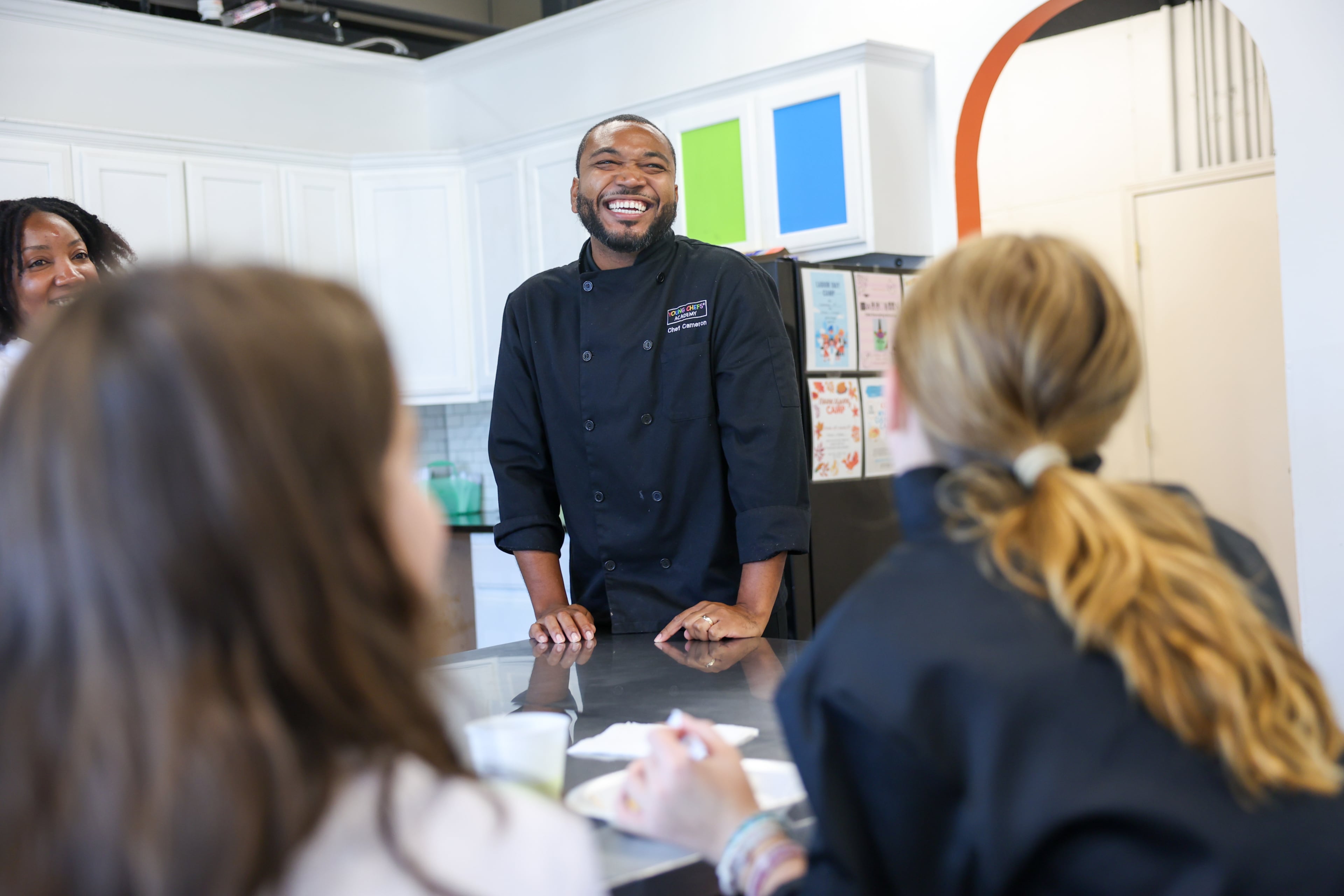 Co-owner Cameron Williams (center) laughs with students at Young Chefs Academy in Sandy Springs on Aug. 20, 2026. (Arvin Temkar/AJC)