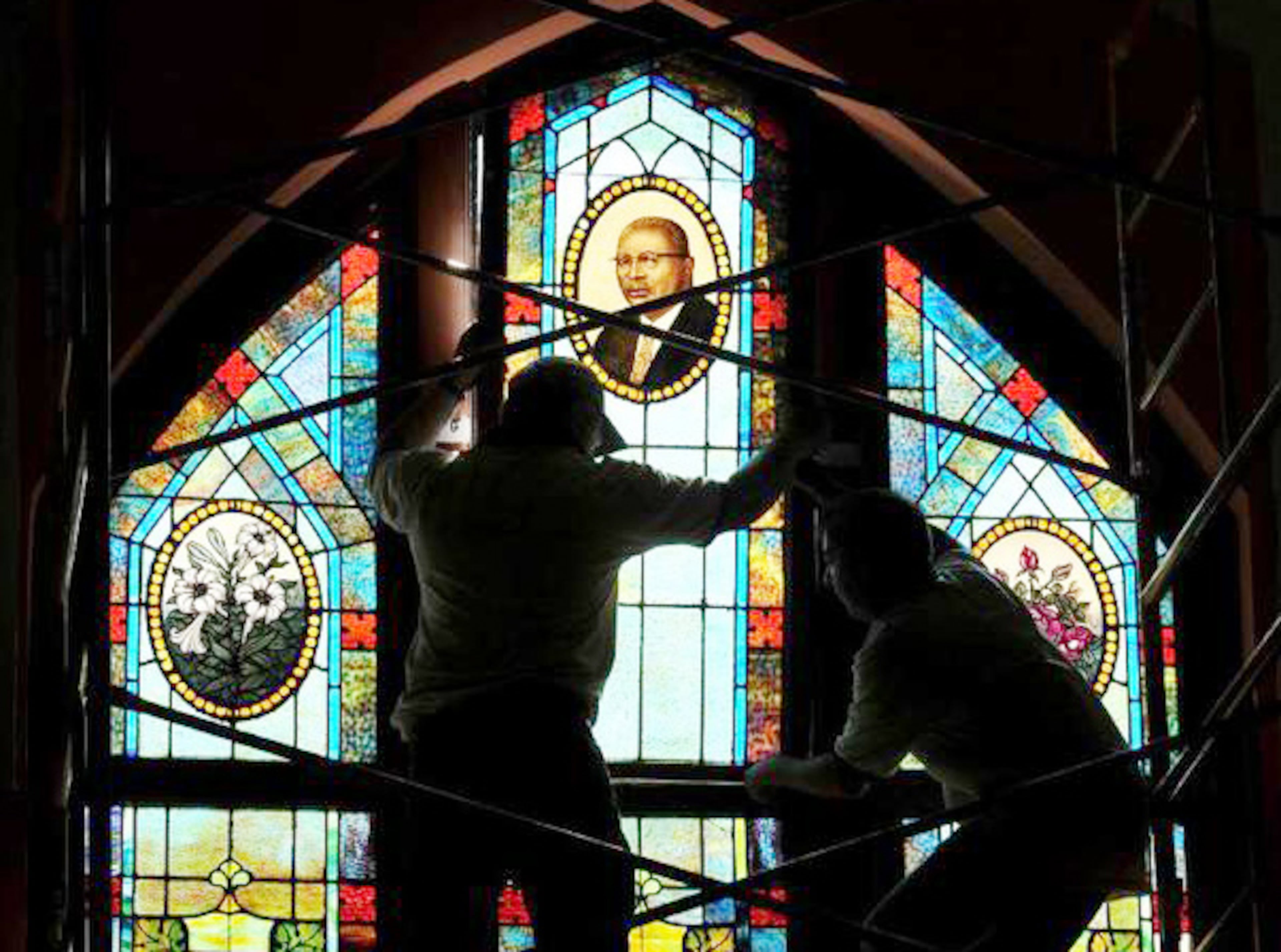 Jeff Speake, owner of Lynchburg Stained Glass, left, and John Beasley install the restored window featuring the image of Rev. Martin Luther King, Sr. at the Historic Ebenezer Baptist Church Wednesday as part of a $4.4 million Phase II restoration project. (Brant Sanderlin/AJC File)