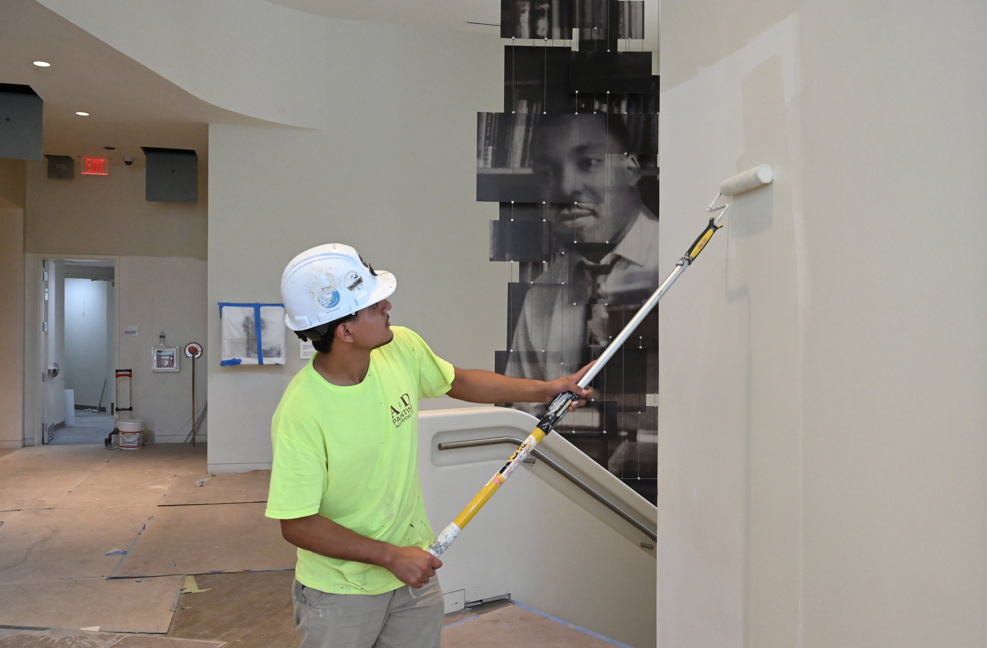 A workers paints a wall at the National Center for Civil and Human Rights near a mural of the Rev. Martin Luther King Jr. The center is moving the King Papers — a collection of the civil rights leader's handwritten sermons, speeches and notes — to a more prominent place. (Hyosub Shin/AJC)