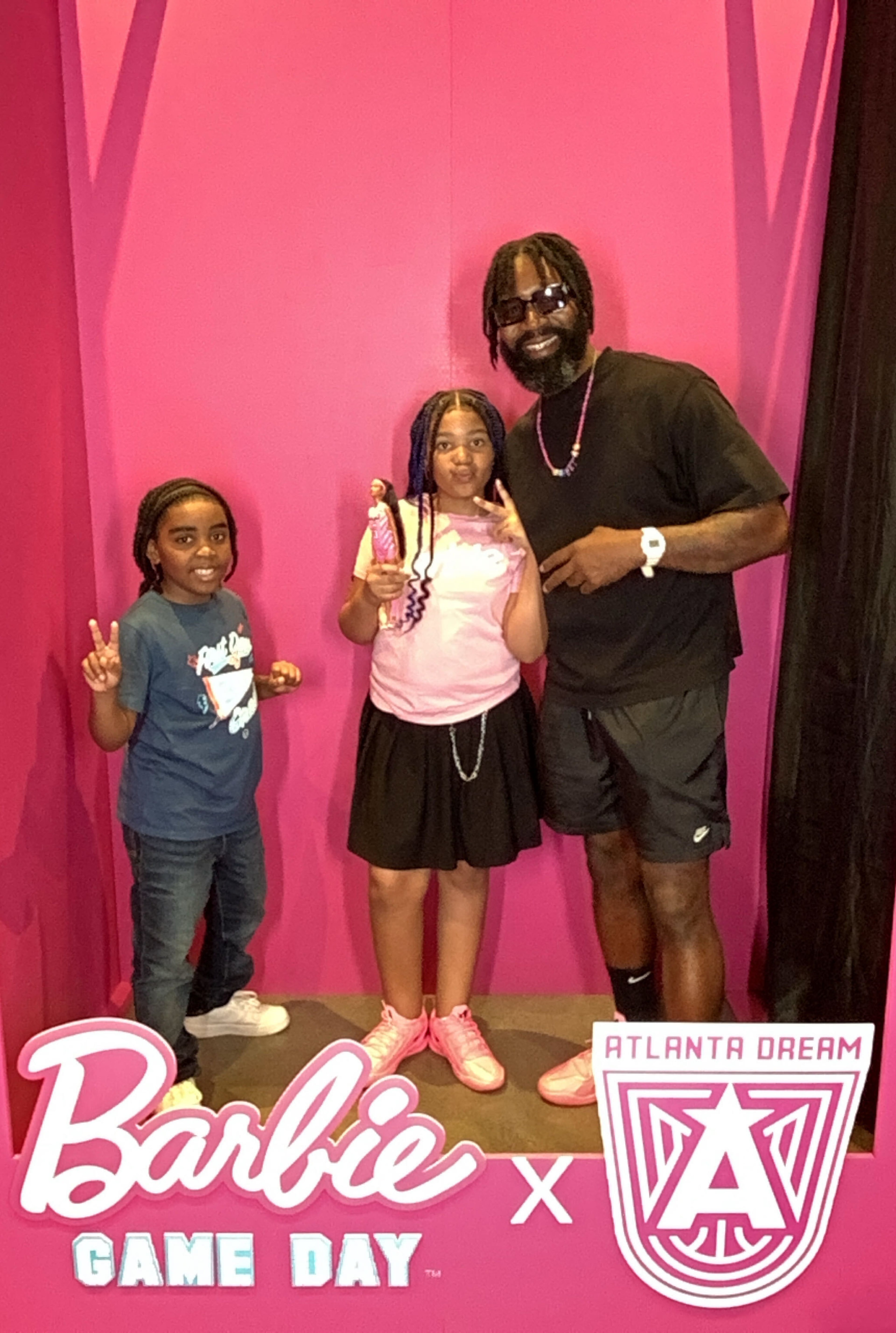 Kai Cannon (center) poses with her Angel Reese Barbie doll, her brother, King, and her father, Kyle. The Dream have embraced the Barbie universe since adding Reese in April. (Courtesy of Kylan Cannon)