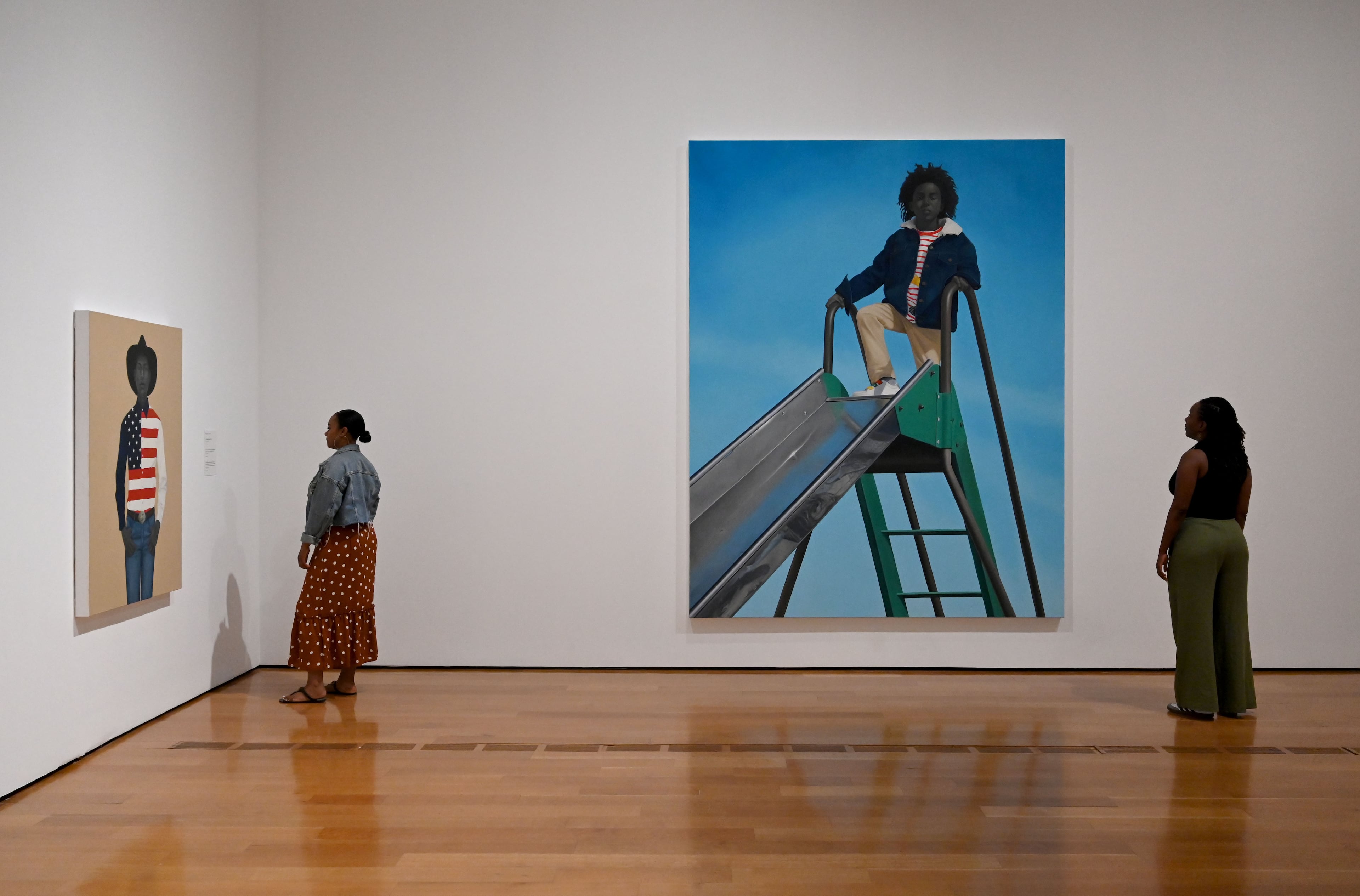 Visitors view Sherald’s paintings — "What’s precious inside of him does not care to be known by the mind in ways that diminish its presence (All American)" at left and "Kingdom" at right — in the “American Sublime” exhibition. (Hyosub Shin/AJC)