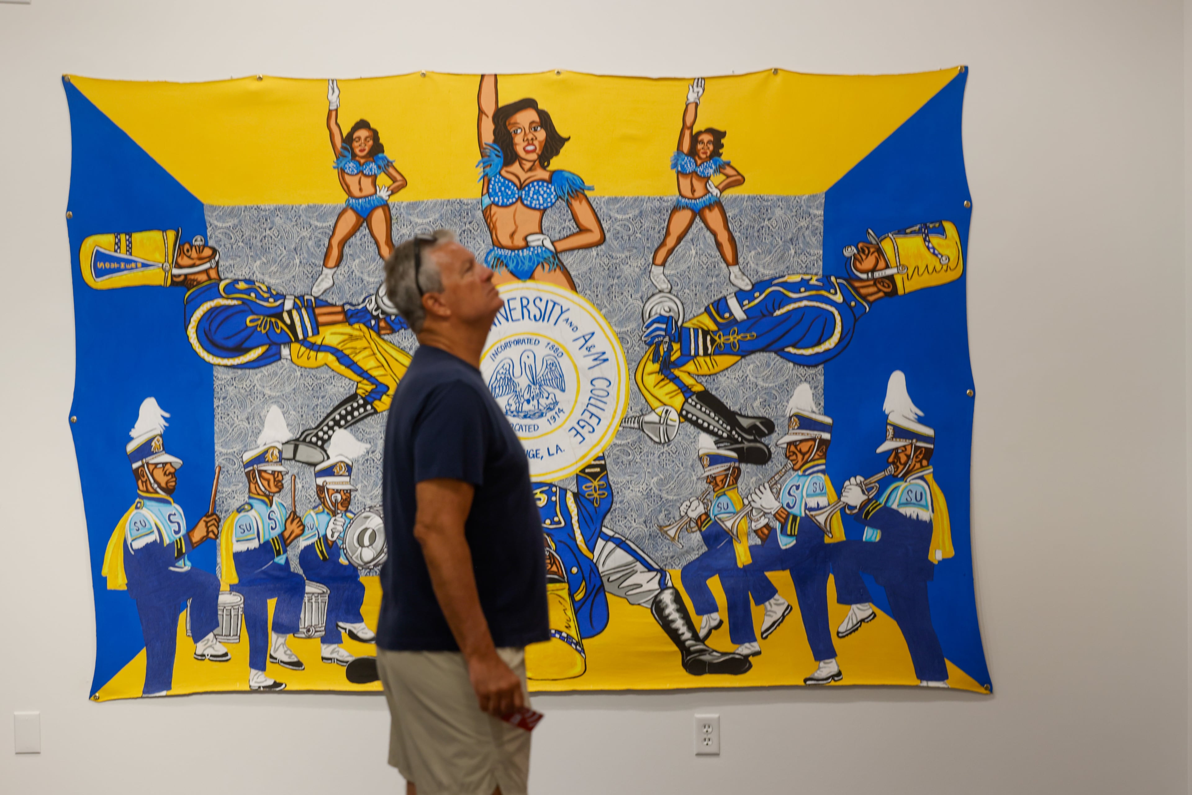 Rudy George checks out artist Keith Duncan’s exhibit “Battle of the Bands,” inspired by HBCU band culture, at the College Football Hall of Fame in Atlanta on Sept. 11, 2026. Duncan utilizes bright colors to convey the competition and pageantry between the bands. (Arvin Temkar/AJC)